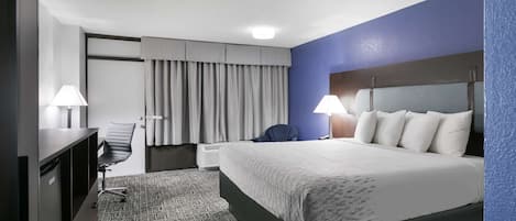 Una habitación de hotel con cama, escritorio, silla y dos lámparas.