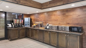 A modern kitchen with wooden cabinets, a granite countertop, and stainless steel appliances including a coffee maker, microwave, and toaster. - SureStay Plus Hotel by Best Western Gatlinburg (Gatlinburg)