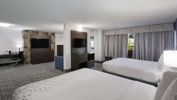 A hotel room with two beds, a TV, a desk, and a stone fireplace. - SureStay Plus Hotel by Best Western Gatlinburg (Gatlinburg)