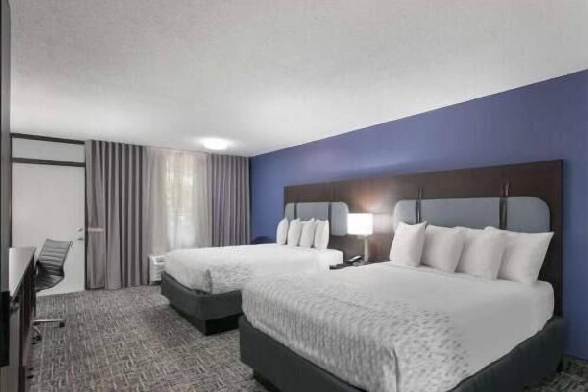 Une chambre d’hôtel avec deux lits, un bureau et une chaise.