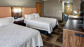 Quarto de hotel com duas camas, uma mesa, uma cadeira e uma televisão.