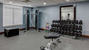 A gym with weightlifting equipment, a bench, and a rack of dumbbells.