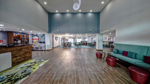 A spacious lobby with a reception desk, seating area, and a decorative ceiling light.