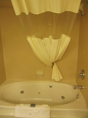 A bathtub with a shower curtain and a towel.