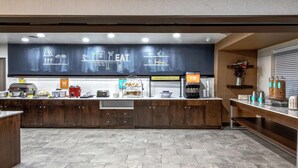 A modern kitchen area with a herringbone tile floor, wooden cabinets, a stainless steel refrigerator, and a coffee machine.
