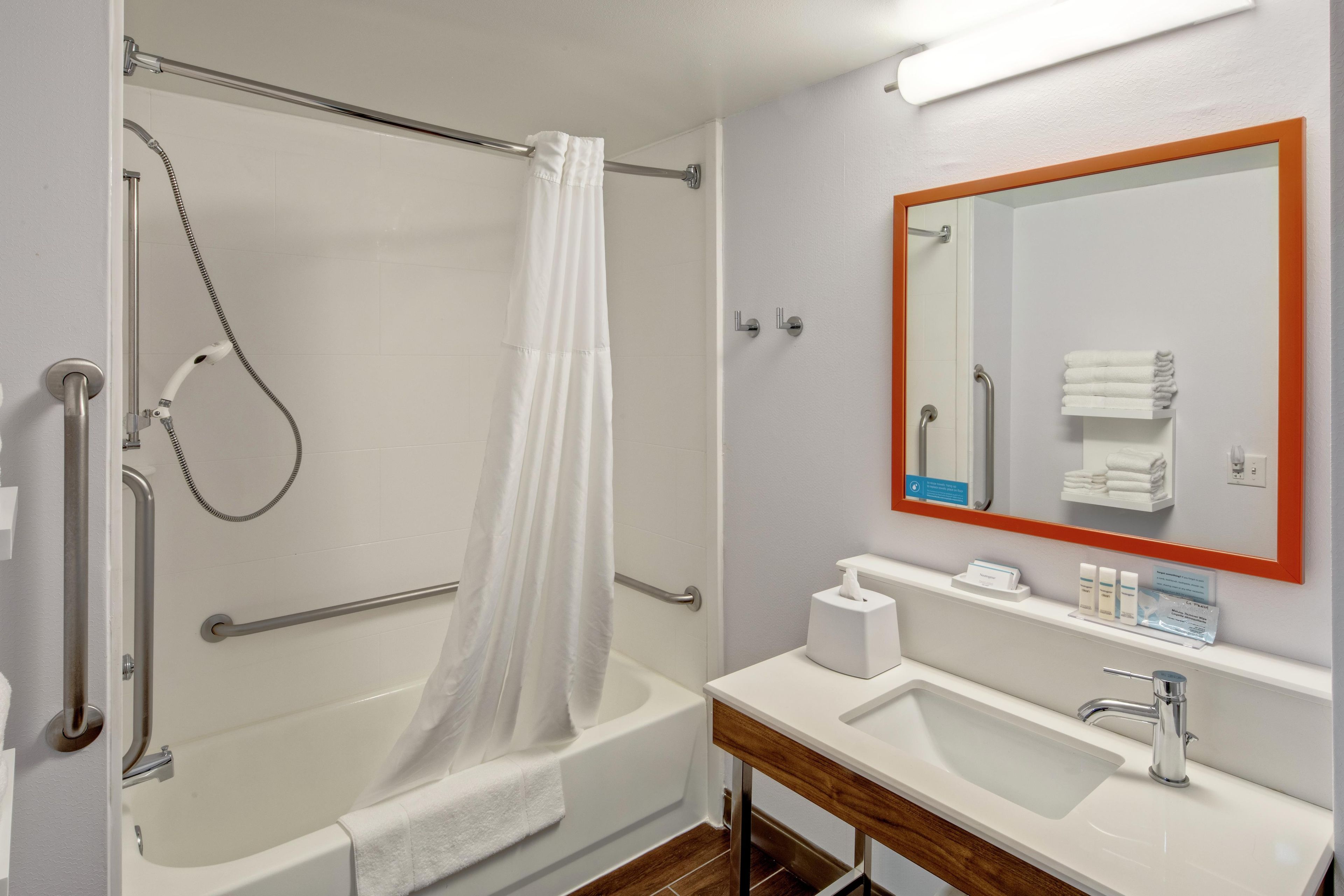Une salle de bain équipée d’une douche, d’un lavabo, d’un miroir et d’un porte-serviettes.