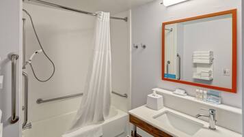 Une salle de bain équipée d’une douche, d’un lavabo, d’un miroir et d’un porte-serviettes.