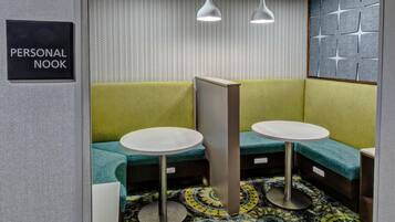A personal nook with two tables and benches, patterned wallpaper, and pendant lighting.