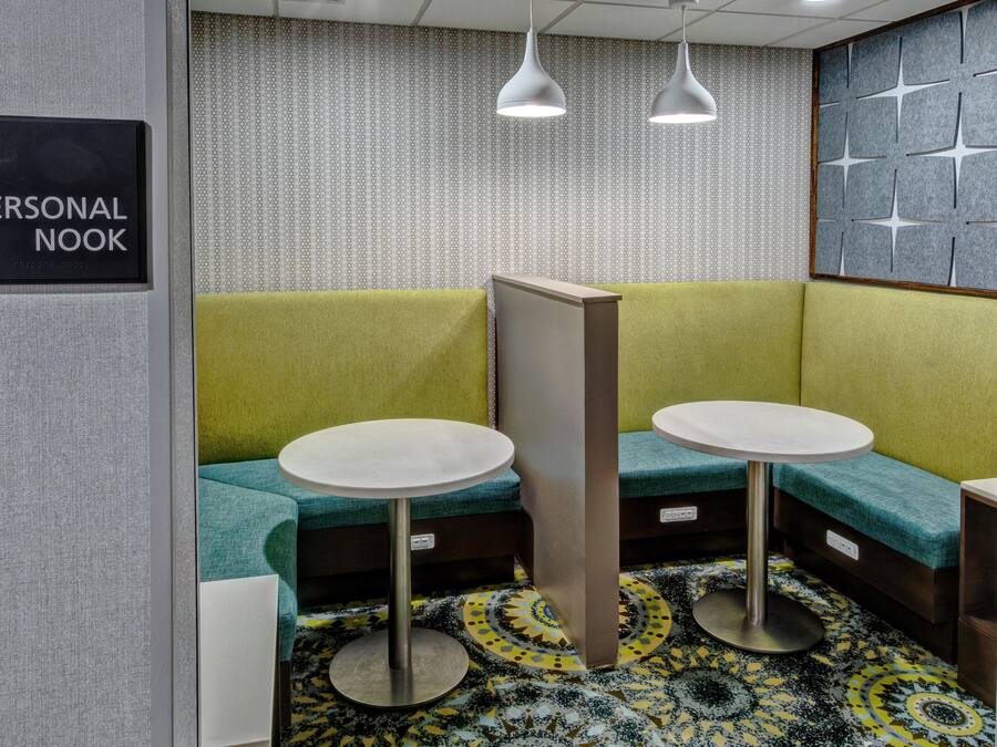 A personal nook with two tables and benches, patterned wallpaper, and pendant lighting.