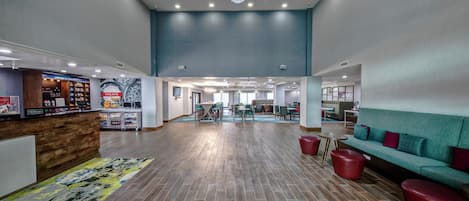 Eine geräumige Lobby mit einer Rezeption, einer Sitzecke und Blick auf den Speisesaal.