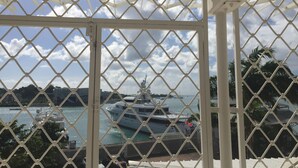 A view through a white metal fence with a diamond pattern, overlooking a marina with boats and yachts. - Saint John Perse (Pointe-à-Pitre)