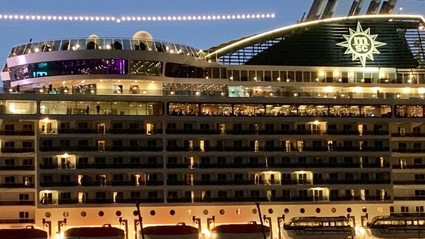A large cruise ship with multiple decks, including a dining area on the upper level and a prominent logo on the side. - Saint John Perse (Pointe-à-Pitre)