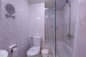A bathroom with a toilet, a bidet, a shower, and a glass-enclosed shower stall.