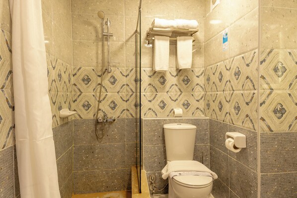 A bathroom with patterned tiles, a shower, a toilet, and a towel rack.