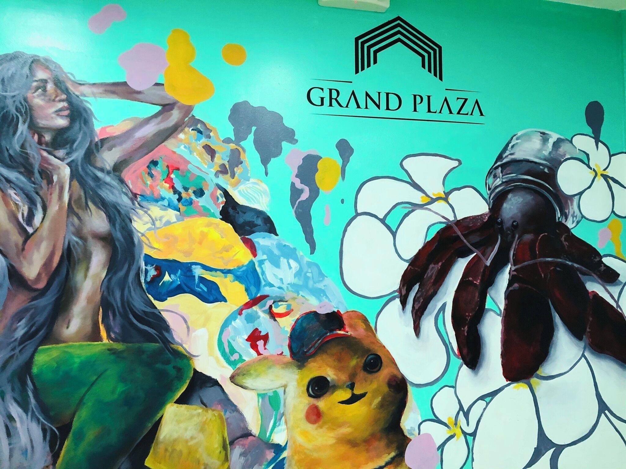A colorful mural with a woman and a crab, and the text "GRAND PLAZA".