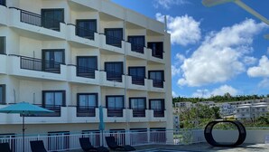 A hotel with a swimming pool, multiple balconies, and lounge chairs. - Grand Plaza Hotel (Tamuning)