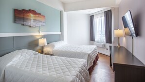 A hotel room with two beds, a TV, and a painting on the wall. - Grand Plaza Hotel (Tamuning)