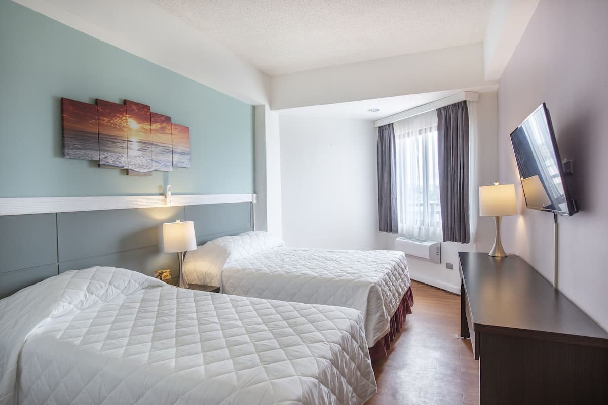 Quarto de hotel com duas camas, televisão e um quadro na parede.