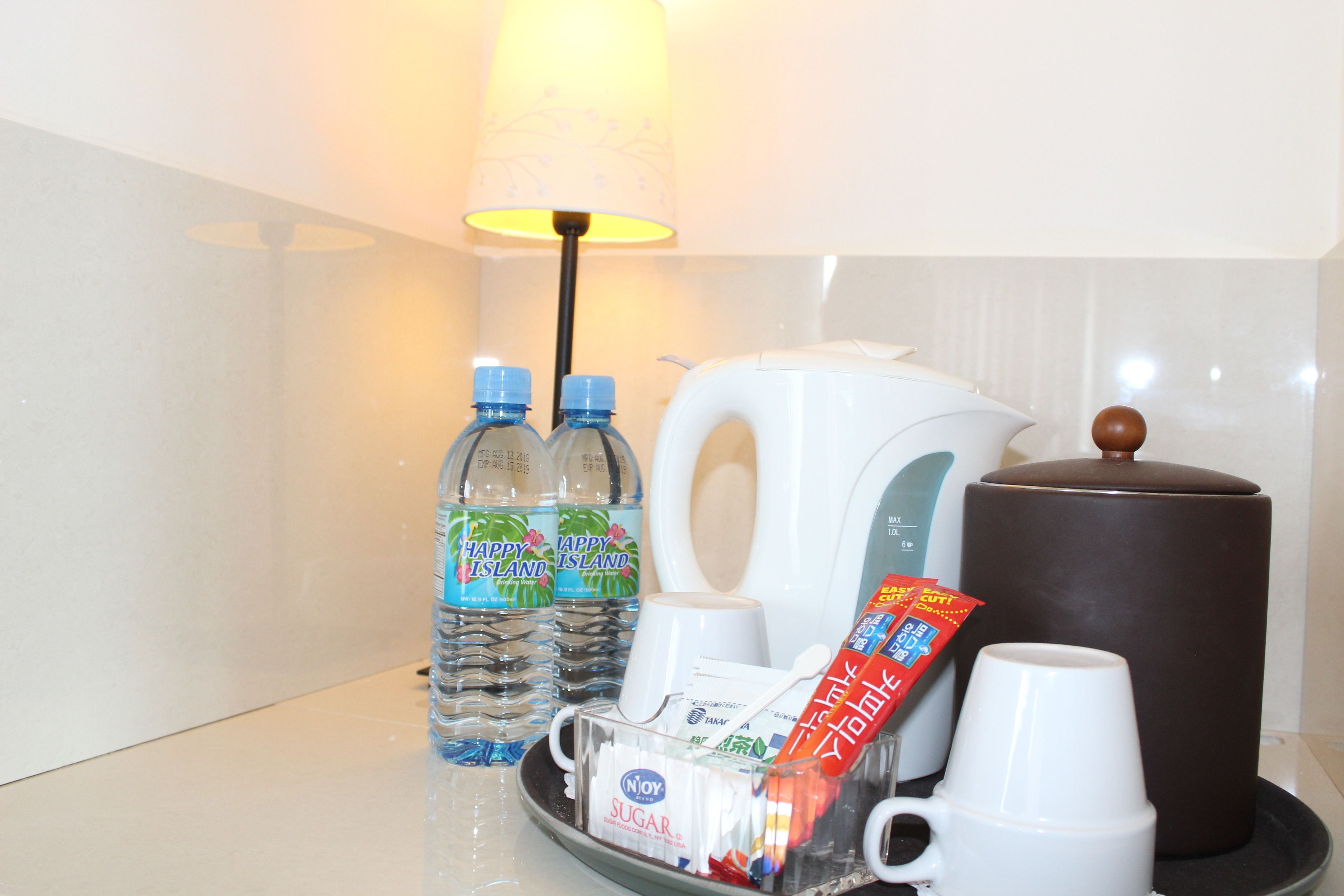 Ontbijtserver in een hotelkamer, met waterflesjes, een koffiezetapparaat, suikerzakjes en wegwerpbekers.