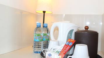 Ontbijtserver in een hotelkamer, met waterflesjes, een koffiezetapparaat, suikerzakjes en wegwerpbekers.