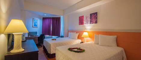 A hotel room with two beds, a desk, a chair, a lamp, and a painting on the wall.