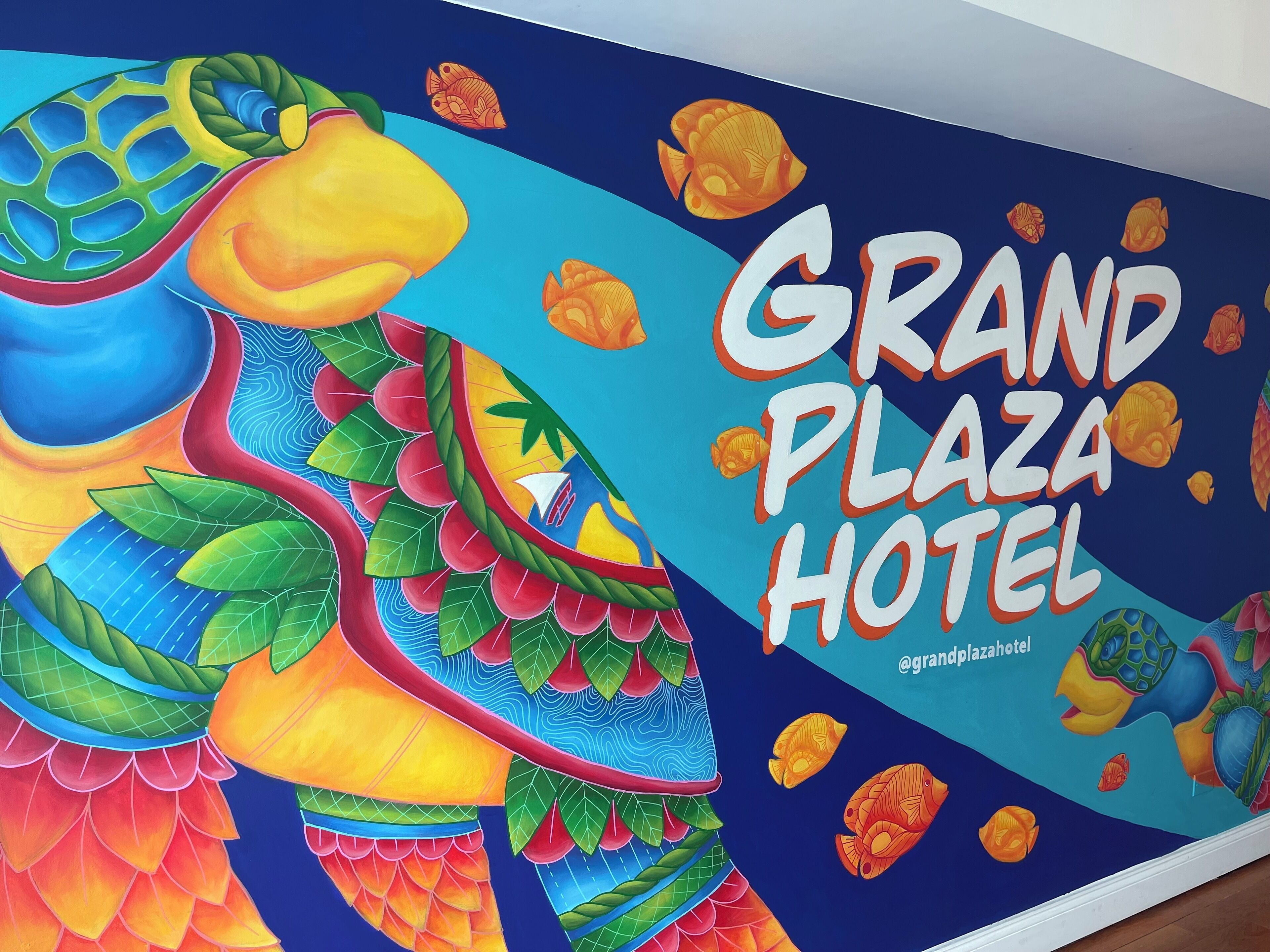 A colorful mural with a tropical theme, including a large fish and the text "Grand Plaza Hotel".
