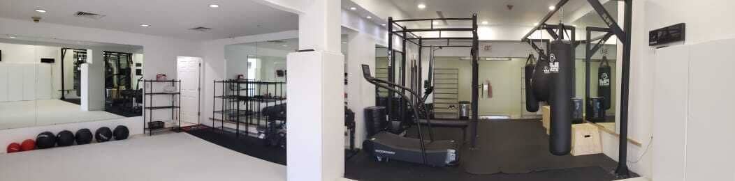 Uma academia com equipamentos de musculação, um espelho e um saco de pancada.