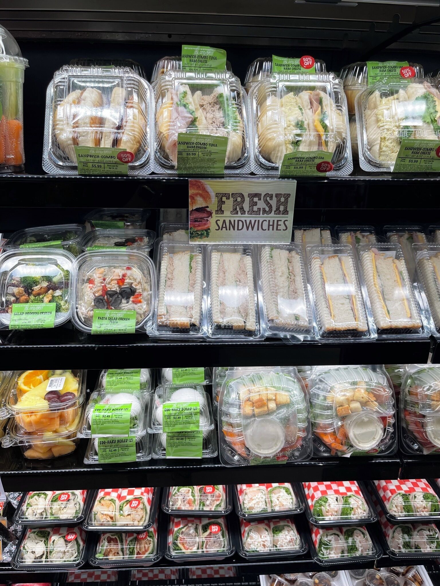 A variety of pre-packaged sandwiches and salads on display in a grocery store.