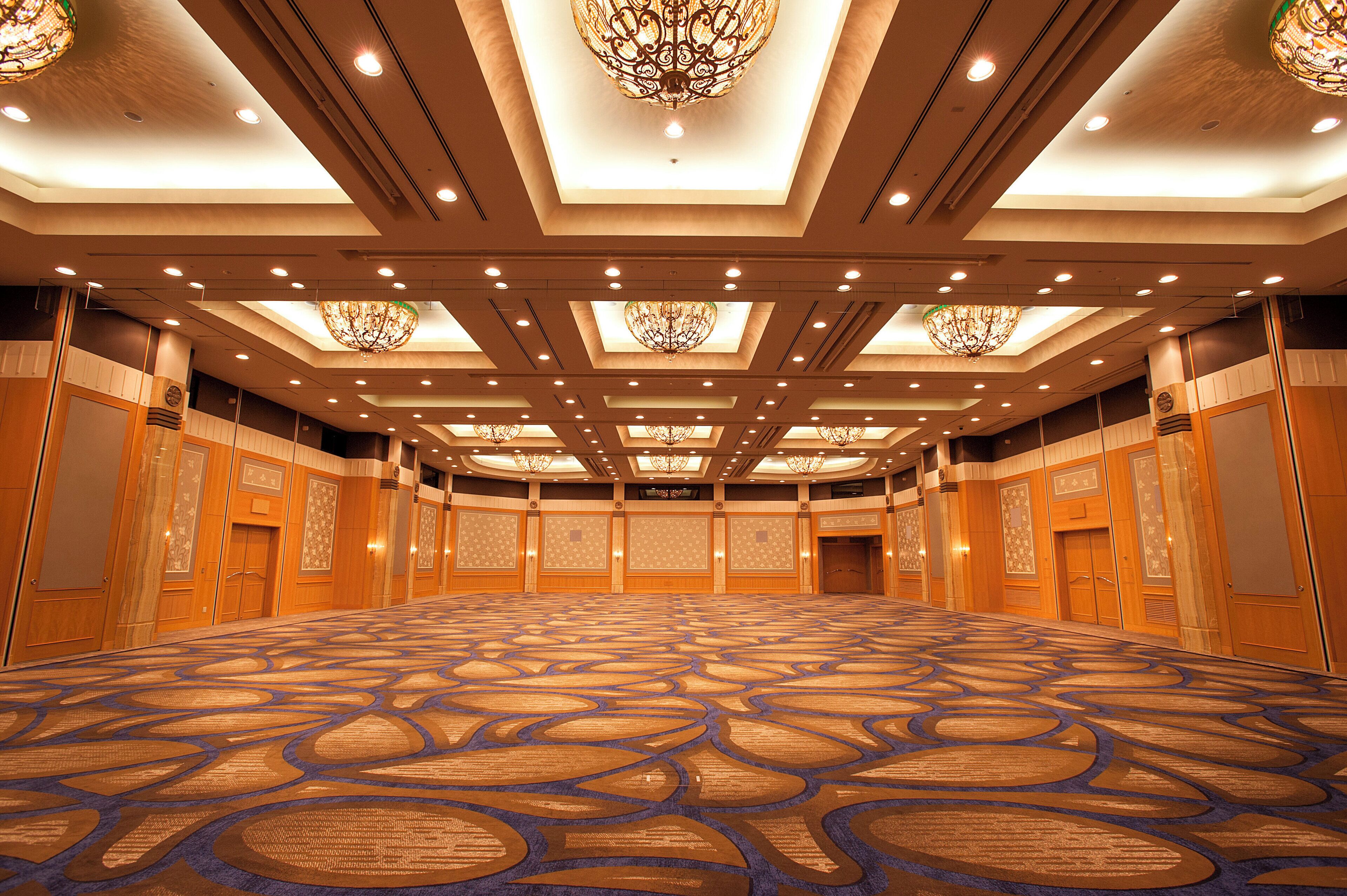 A large, empty conference room with patterned carpet, wooden paneling, and ornate chandeliers.