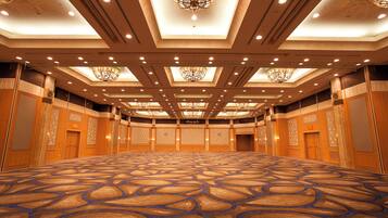 A large, empty conference room with patterned carpet, wooden paneling, and ornate chandeliers.