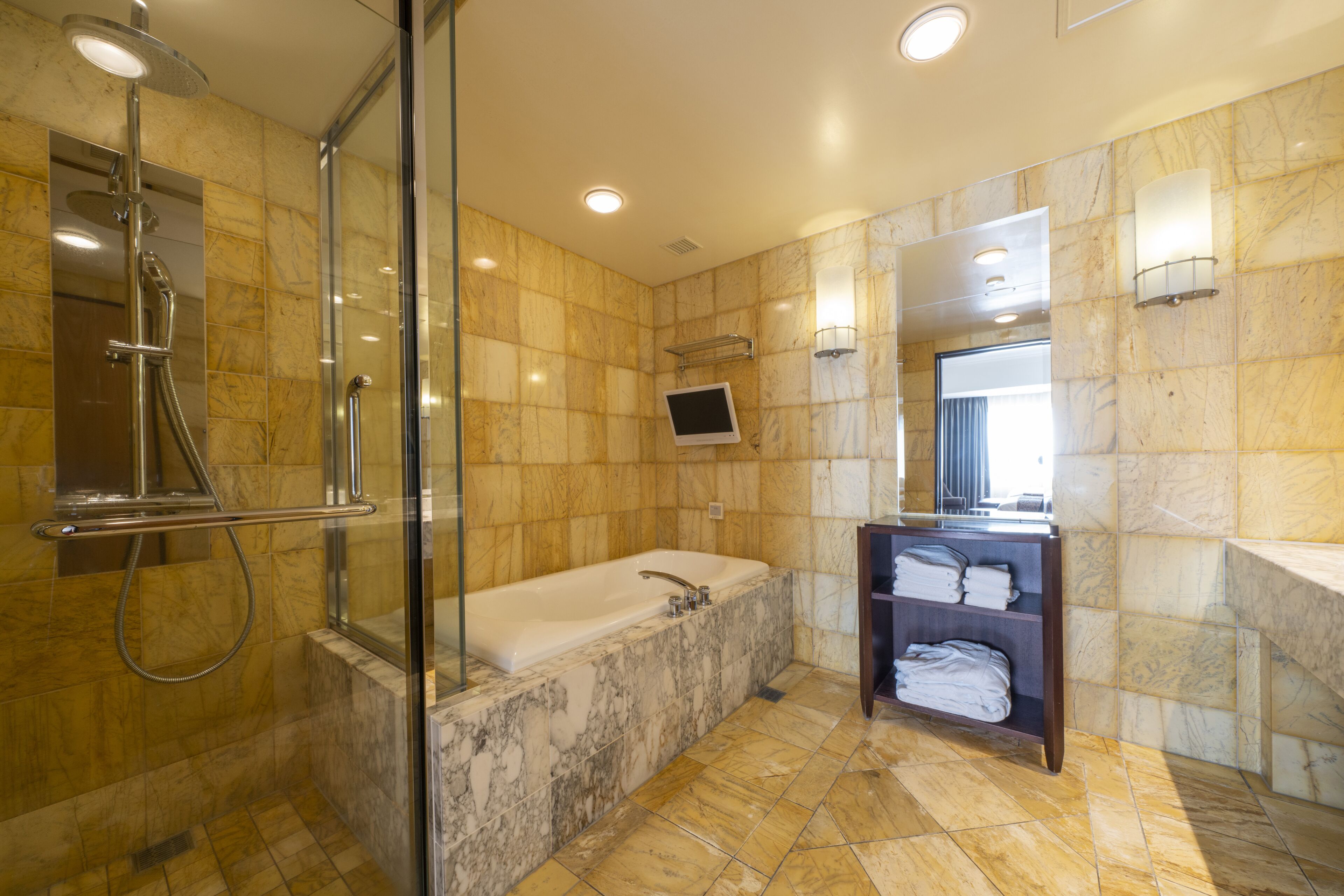 A modern bathroom with a glass-enclosed shower, a freestanding bathtub, and a vanity with a mirror.