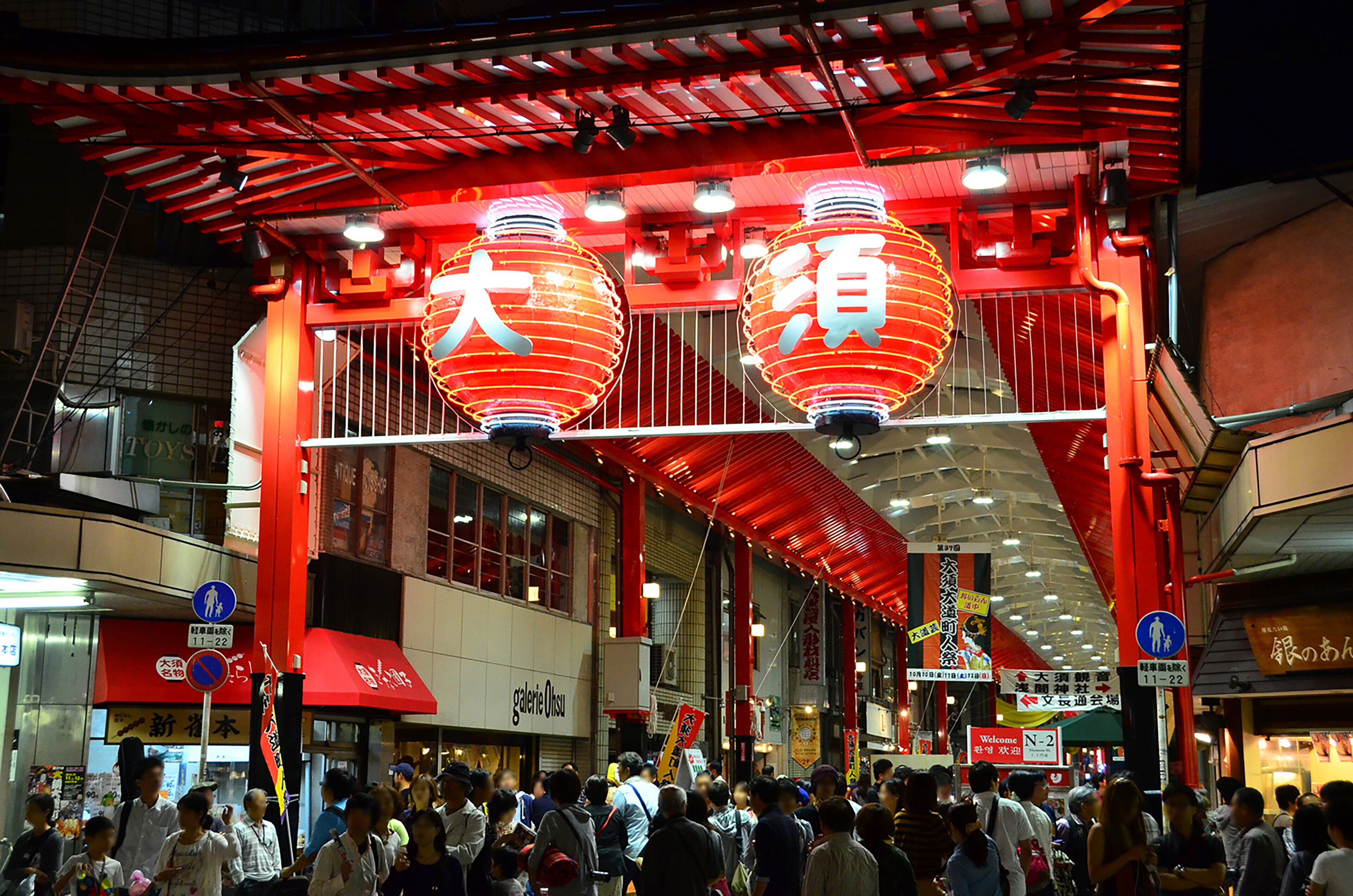 A crowded urban street with red lanterns and signage in a foreign language.