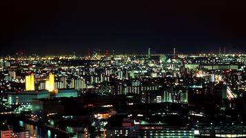 A nighttime cityscape with illuminated buildings and a Ferris wheel.