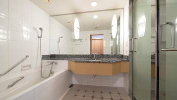 A modern bathroom with a glass shower enclosure, a white bathtub, and a granite countertop sink.