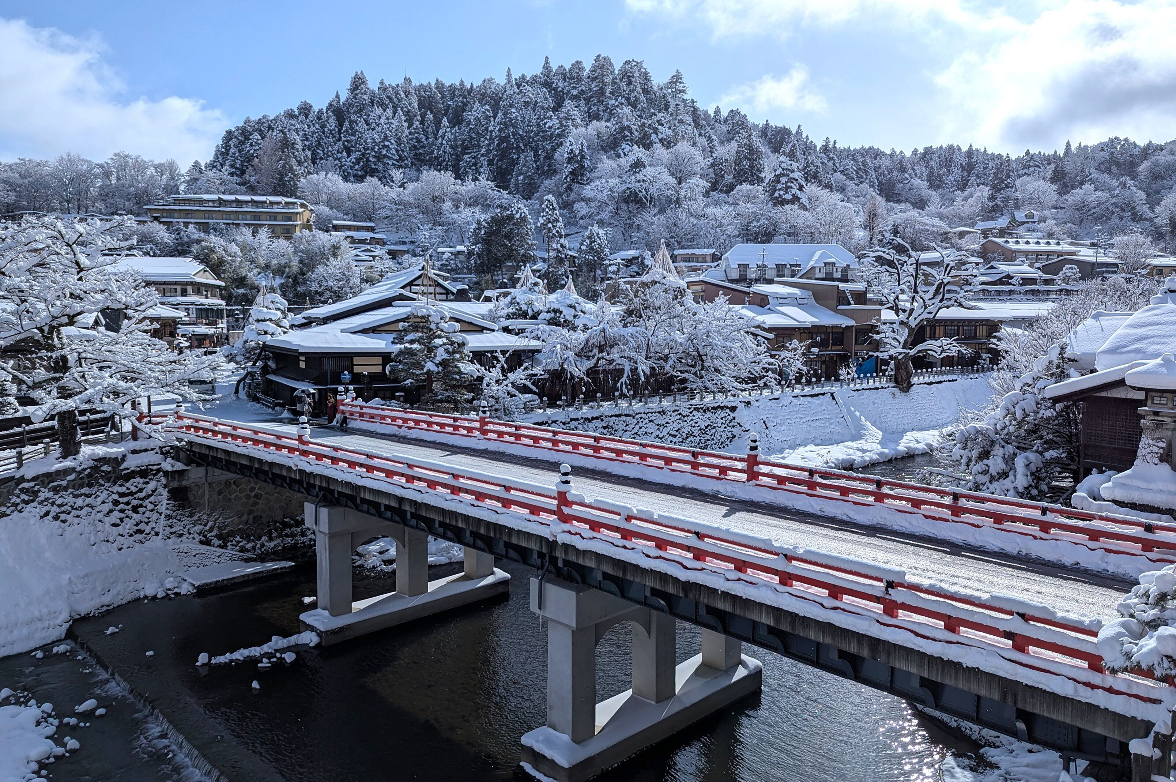 Un puente cubierto de nieve sobre un río, con edificios tradicionales al fondo.
