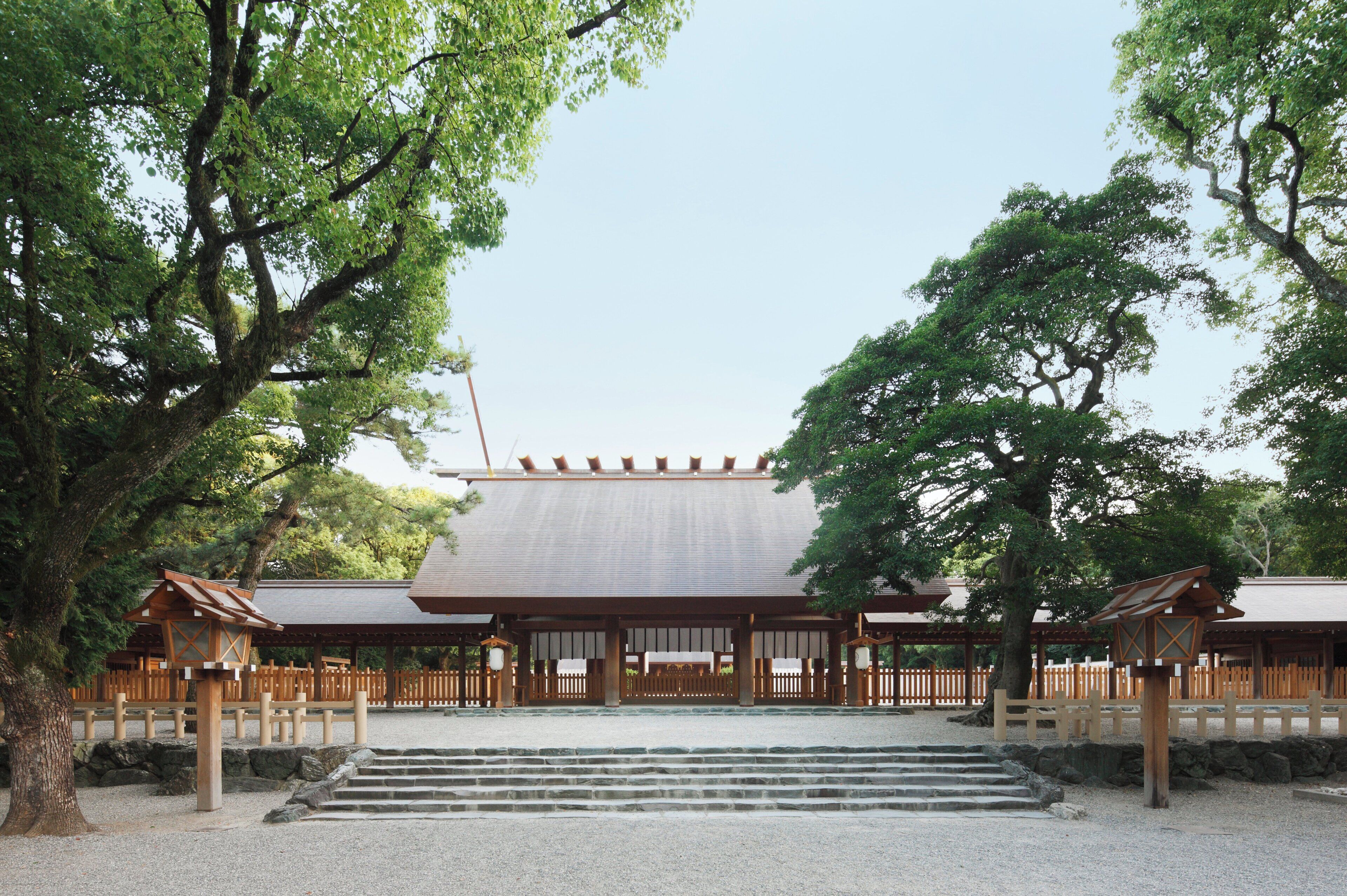 Un edificio japonés tradicional con tejado de tejas, estructura de madera y un sendero de grava que conduce a la entrada.