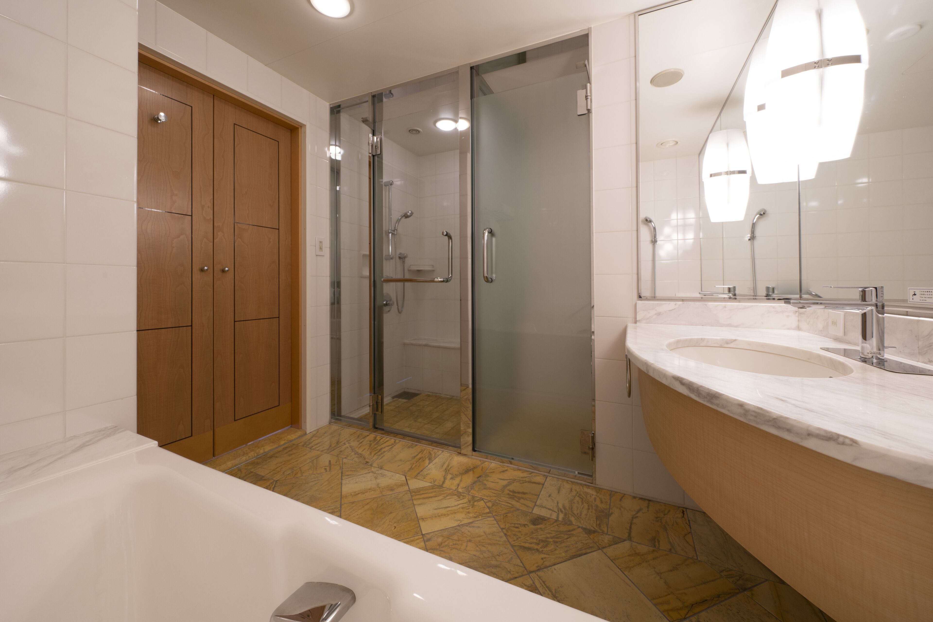 A modern bathroom with a bathtub, a glass-enclosed shower, and a vanity with two sinks.