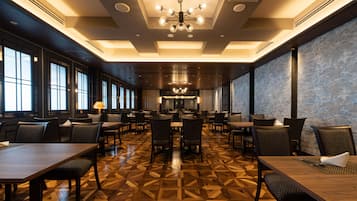 A spacious dining area with multiple tables and chairs, large windows, and a patterned floor.