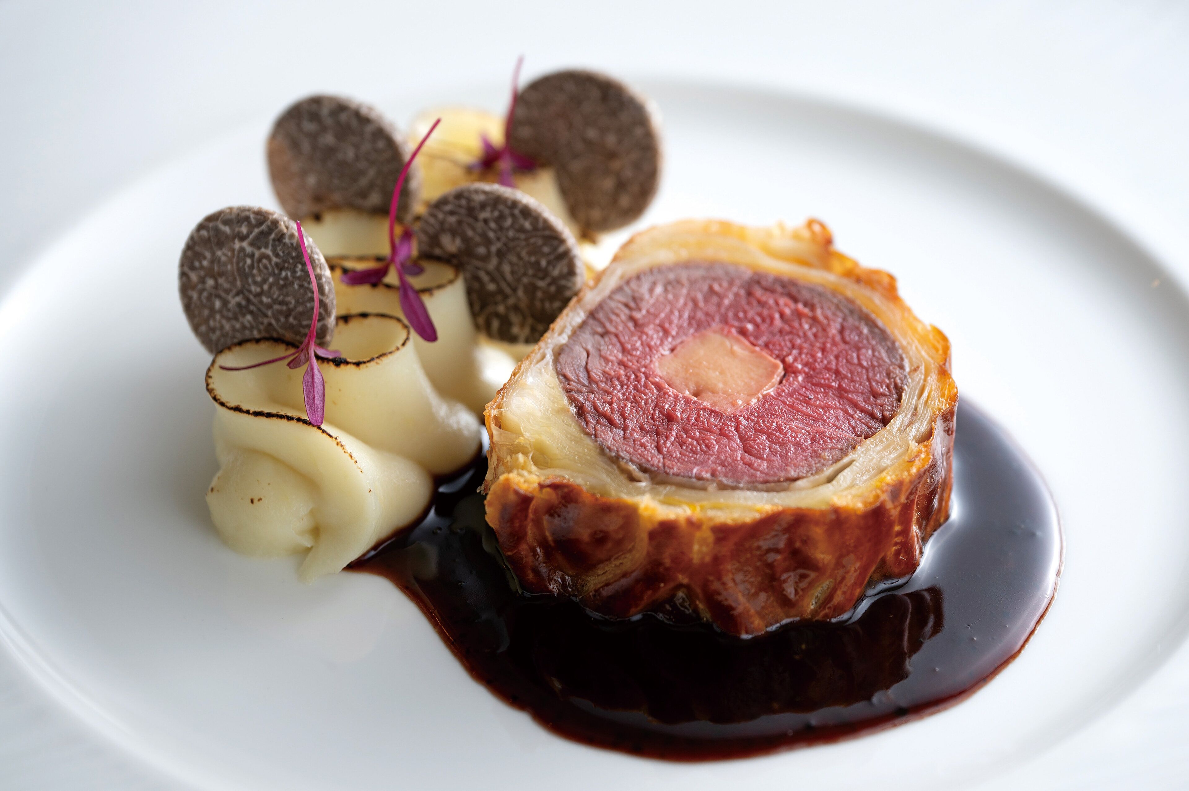 Un plat composé d’une tranche de viande, d’aliments de forme ronde et d’un accompagnement crémeux.