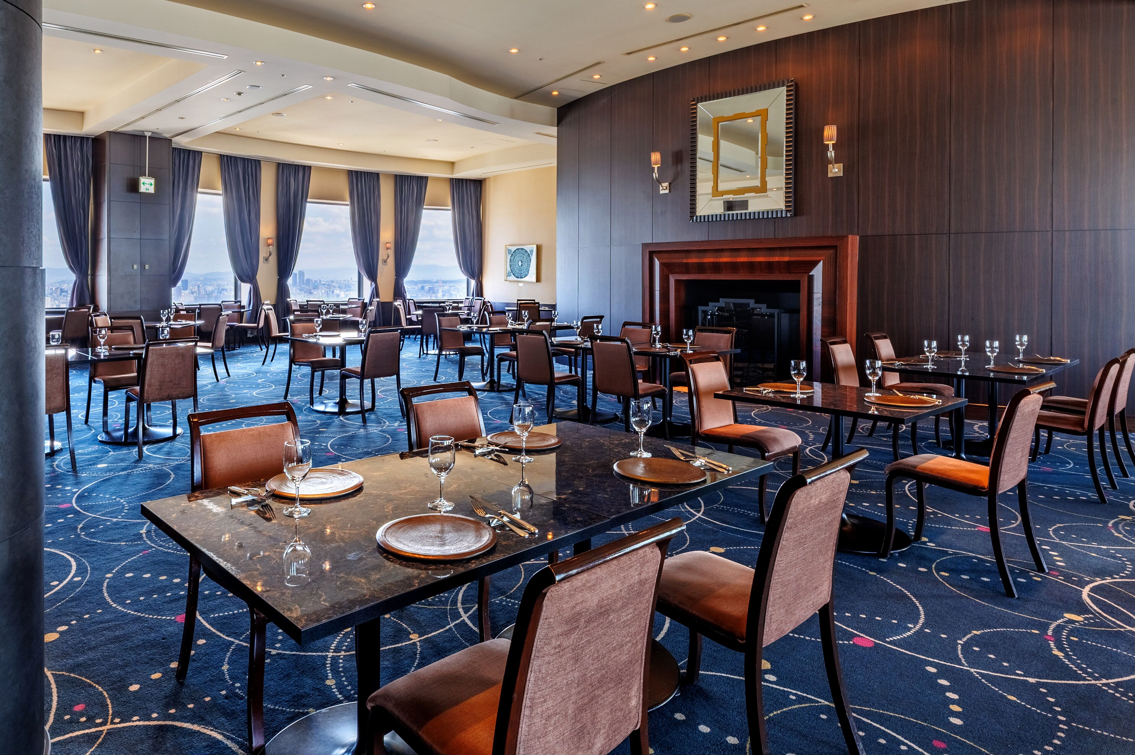 Un comedor de hotel con varias mesas, sillas y una chimenea.