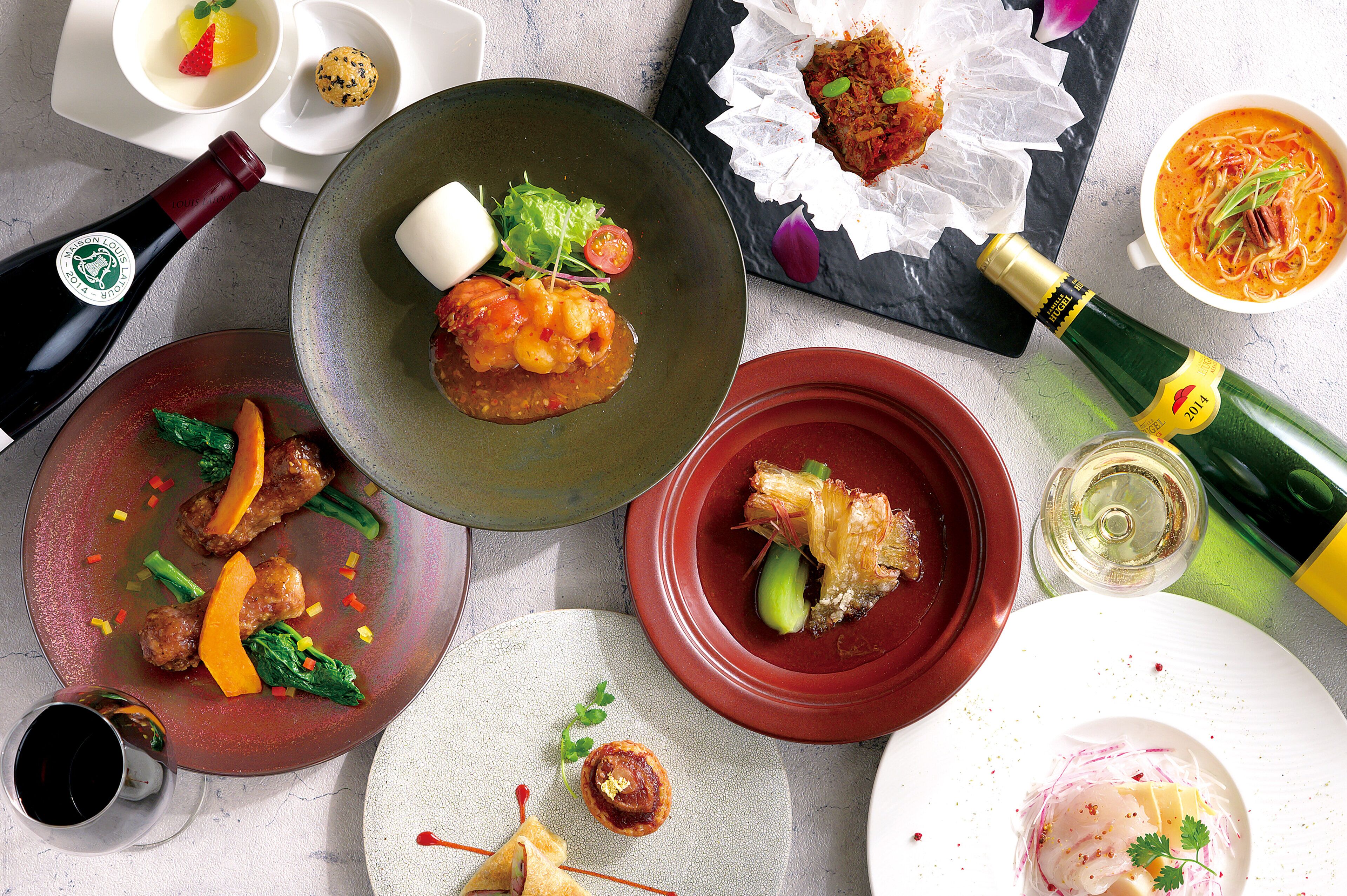 A variety of dishes on plates, a bottle of wine, and a glass of wine.