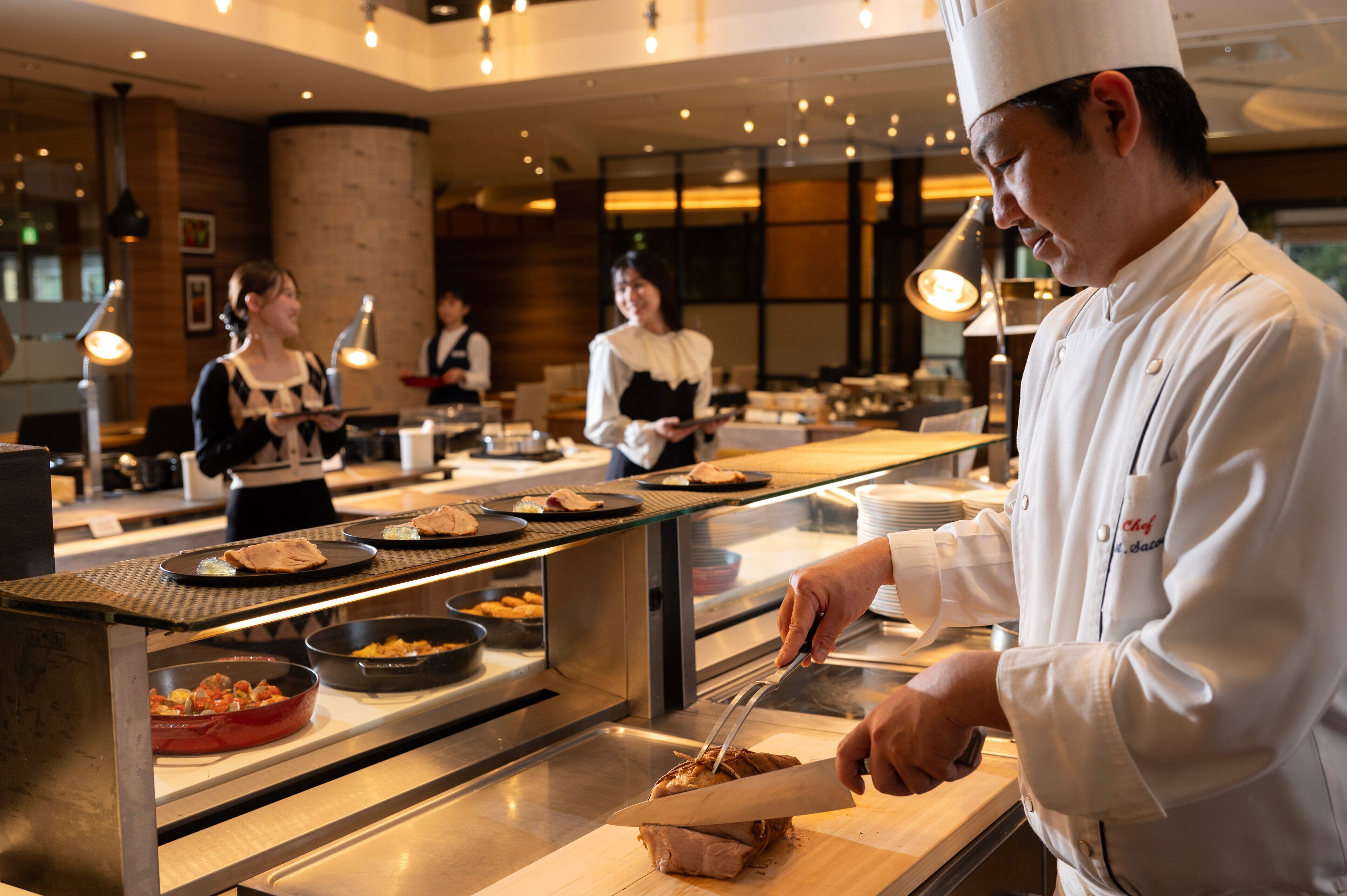 A chef preparing food in a commercial kitchen with stainless steel counters and overhead lighting.