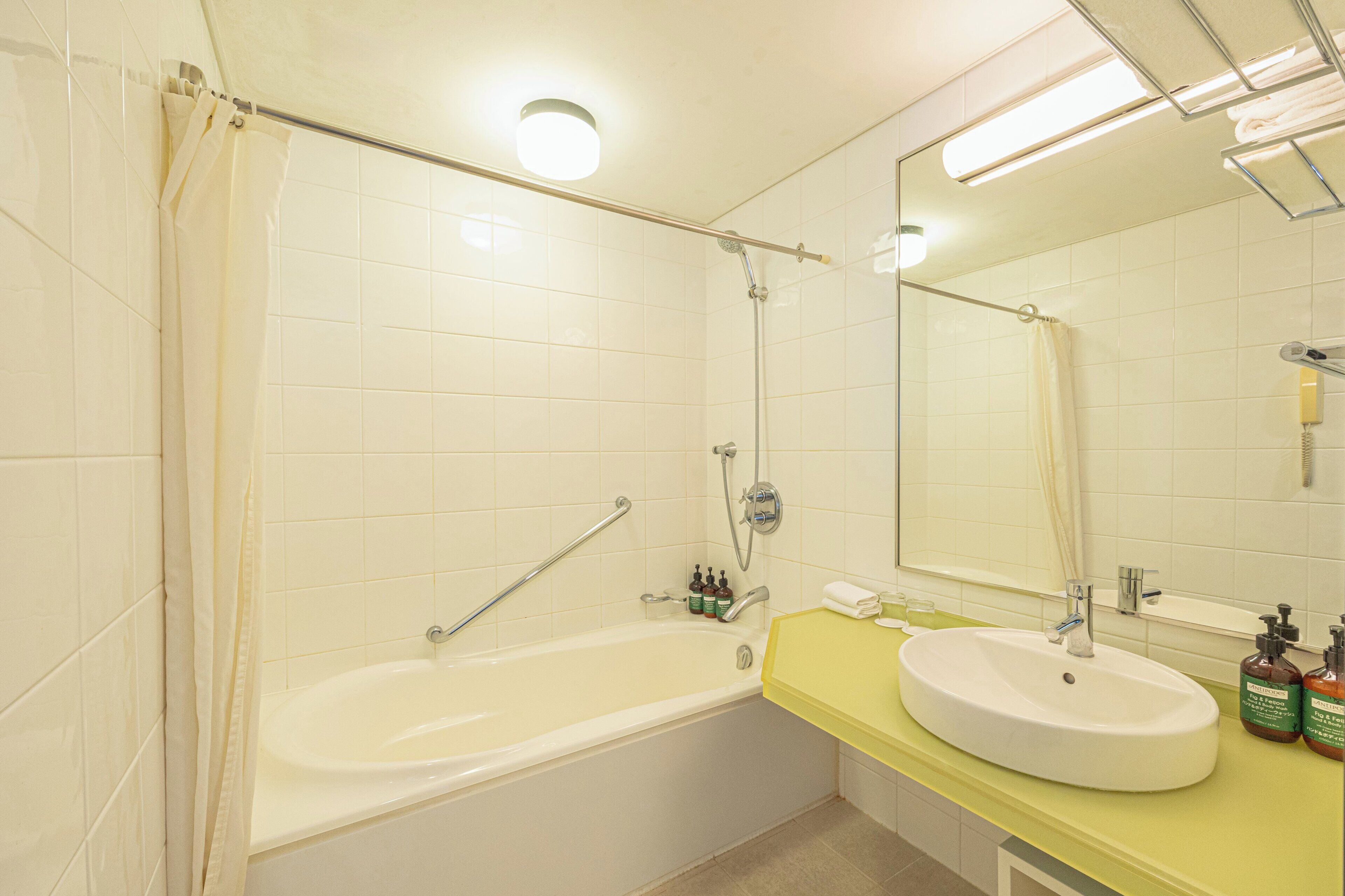 A bathroom with a bathtub, a sink, a mirror, and a shower curtain.