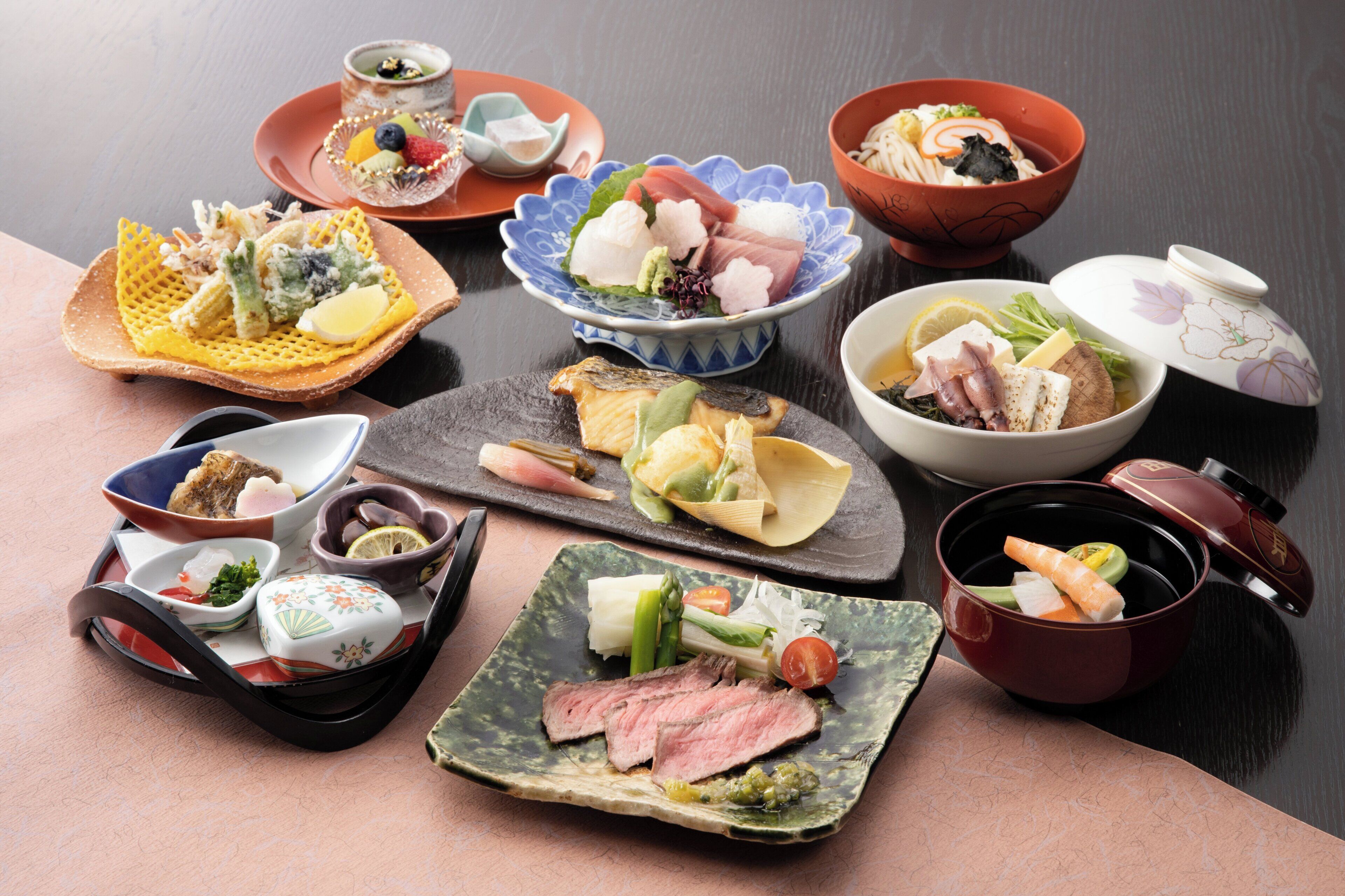 A variety of dishes on a table, including sushi, sashimi, and other Japanese cuisine.