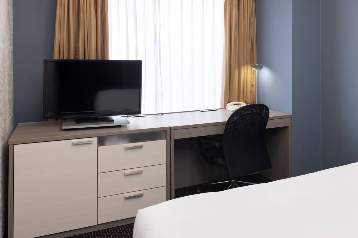 Una habitación de hotel con escritorio, silla, televisión y teléfono.