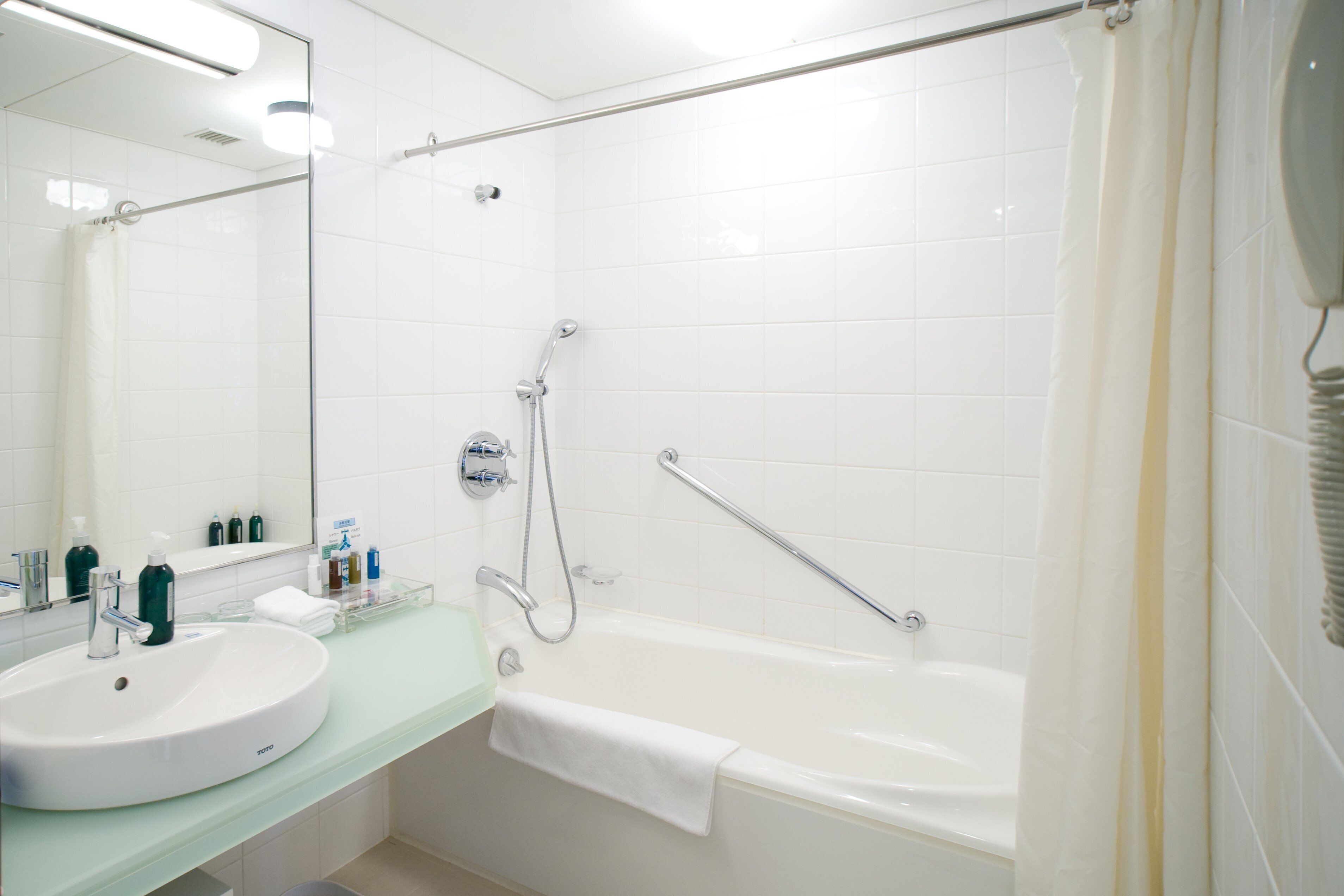 A bathroom with a white sink, mirror, and bathtub.