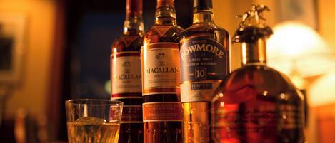 Een aantal whiskyflessen en een glas op een barkruk.