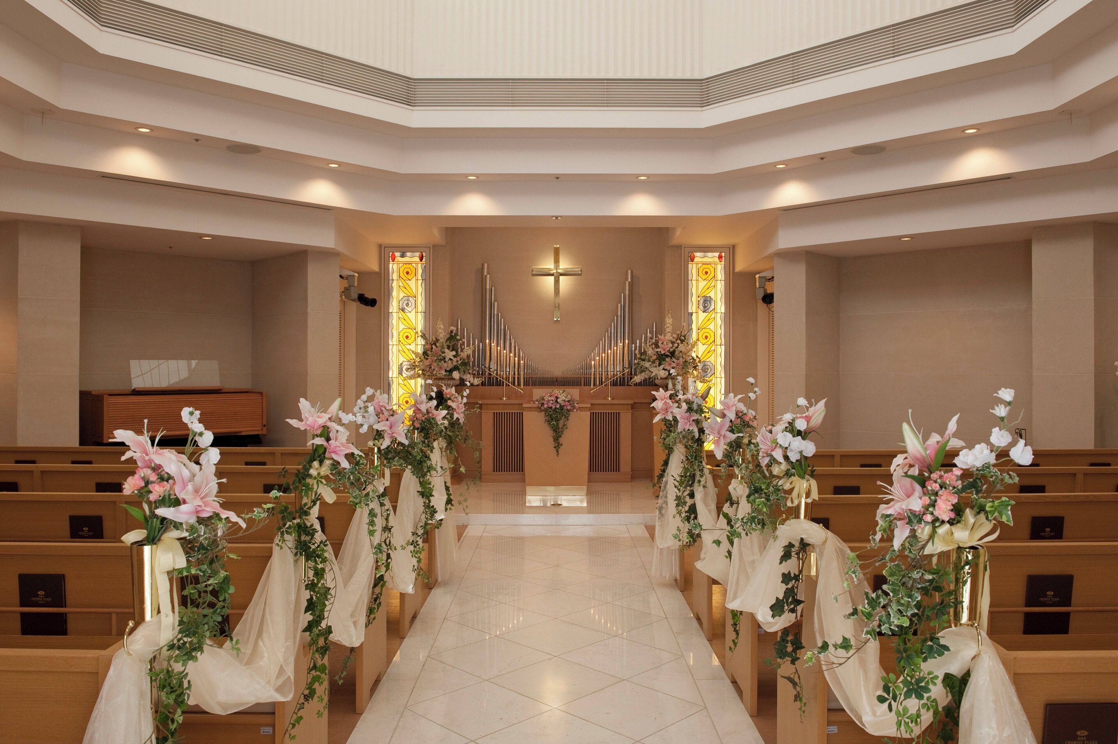 A church interior with pews, a cross, and floral decorations.