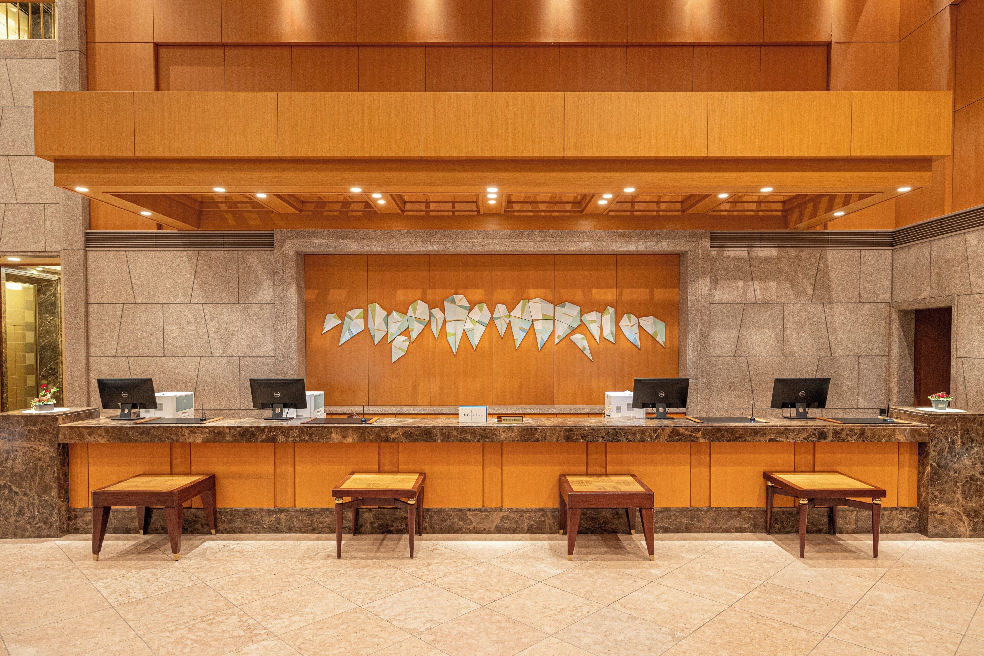 A reception desk with a stone wall backdrop, multiple computer monitors, and wooden benches.