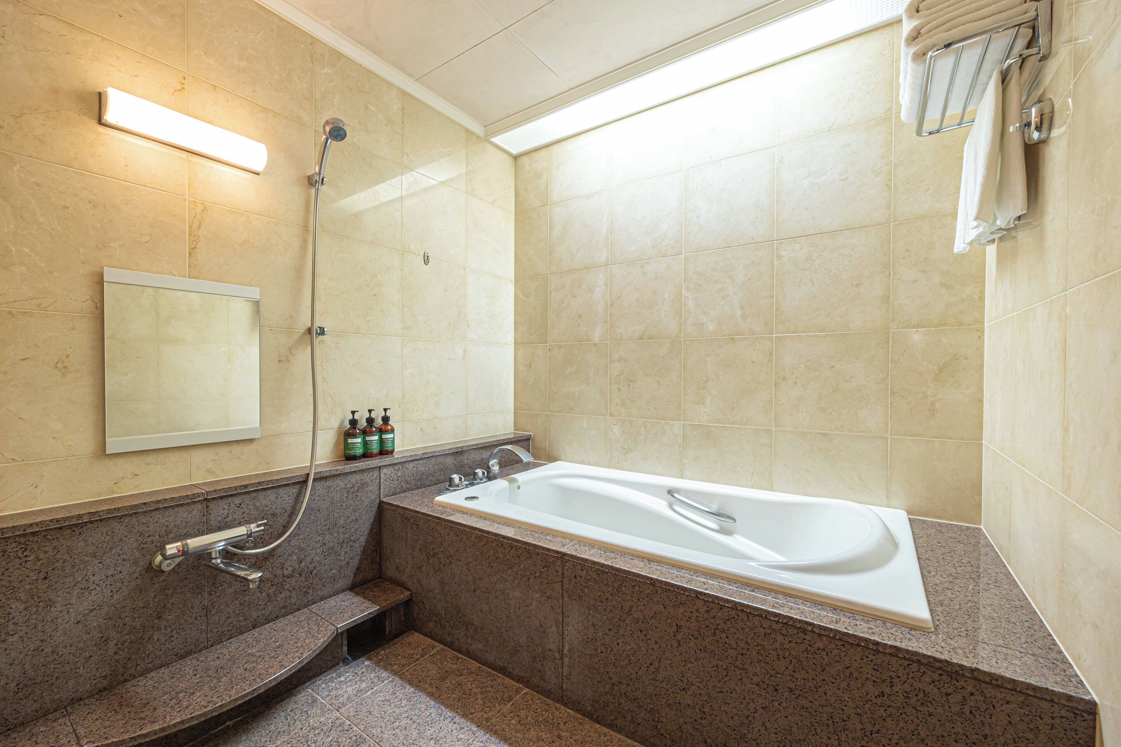 Un baño con bañera, ducha, toallero y espejo.